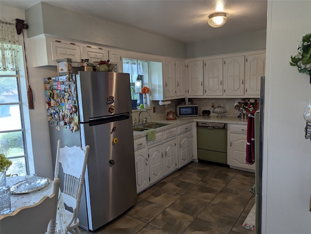 kitchen featuring dark tile patterned floors, appliances with stainless steel finishes, tasteful backsplash, sink, and white cabinetry