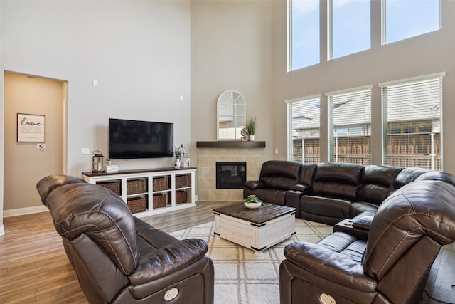 living room featuring a fireplace, light hardwood / wood-style flooring, and a high ceiling