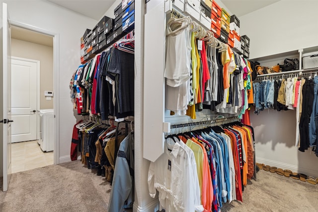 walk in closet with light colored carpet and washer and dryer