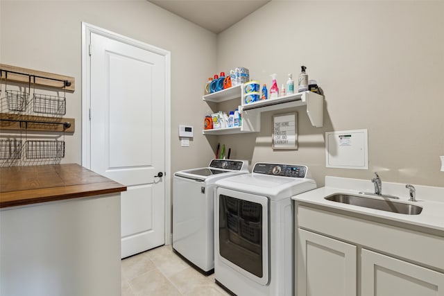 laundry room featuring washing machine and dryer, cabinets, sink, and light tile patterned floors