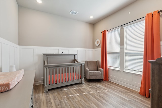 bedroom with light wood-type flooring and a crib