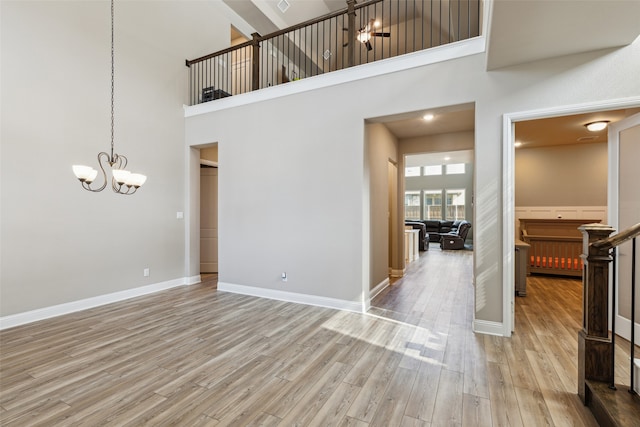 interior space with a high ceiling, an inviting chandelier, and light wood-type flooring