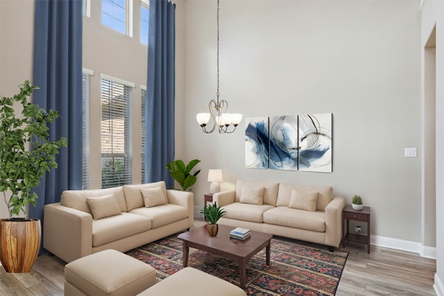 living room featuring a high ceiling, a chandelier, and light hardwood / wood-style floors