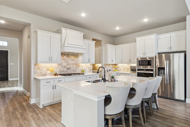 kitchen featuring custom range hood, stainless steel appliances, a kitchen island with sink, and sink