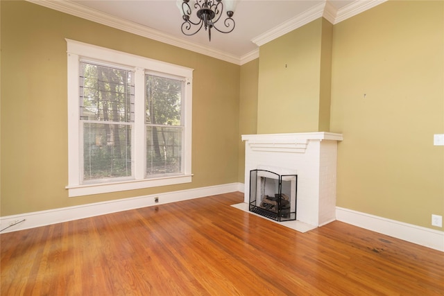 unfurnished living room with hardwood / wood-style flooring, a fireplace, a chandelier, and ornamental molding