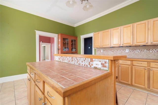 kitchen featuring a center island, decorative backsplash, ornamental molding, light tile patterned floors, and tile counters