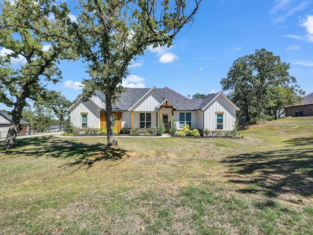 modern farmhouse style home featuring board and batten siding, a front lawn, and roof with shingles