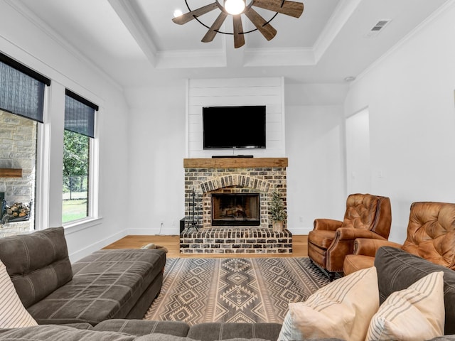 living area with visible vents, wood finished floors, a fireplace, and ornamental molding