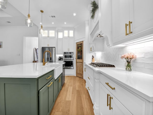 kitchen featuring green cabinets, ornamental molding, white cabinets, stainless steel appliances, and a sink