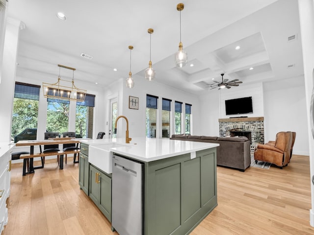 kitchen with green cabinets, dishwasher, a fireplace, and a sink