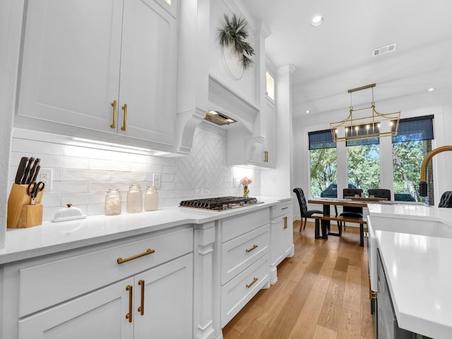 kitchen with light countertops, white cabinets, visible vents, and stainless steel gas cooktop