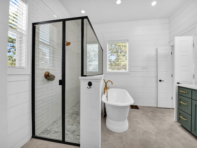 full bath featuring a stall shower, recessed lighting, wood walls, a freestanding bath, and vanity