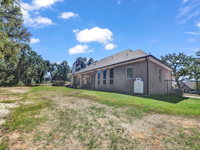 back of house with a yard, fence, brick siding, and cooling unit