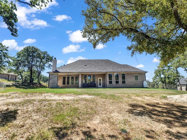 rear view of property with a yard, a chimney, and fence