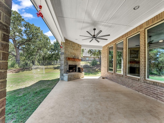 view of patio featuring an outdoor stone fireplace, ceiling fan, and fence