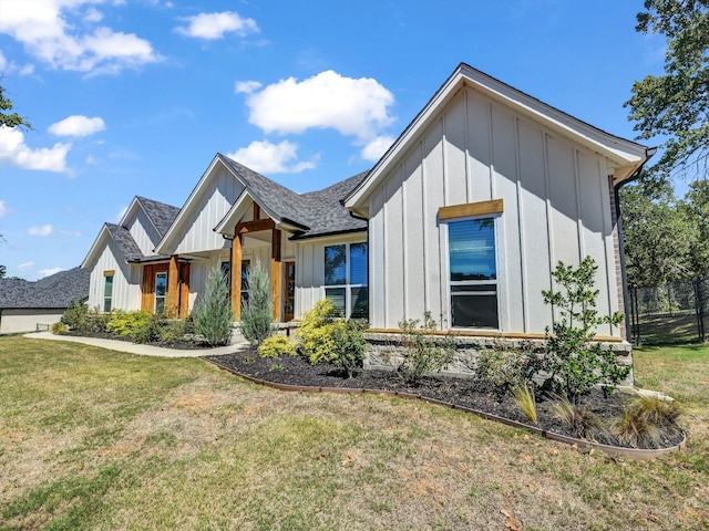 modern farmhouse style home featuring board and batten siding, a front lawn, and roof with shingles