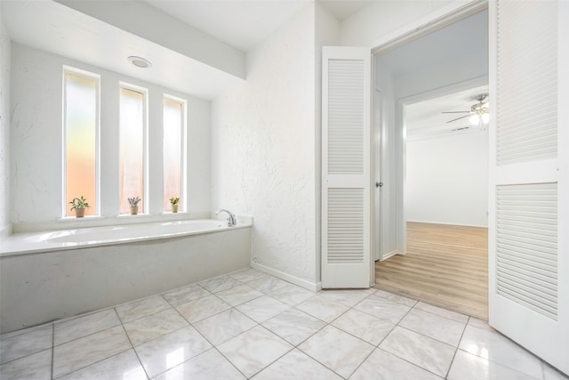 bathroom with a washtub, hardwood / wood-style flooring, and ceiling fan