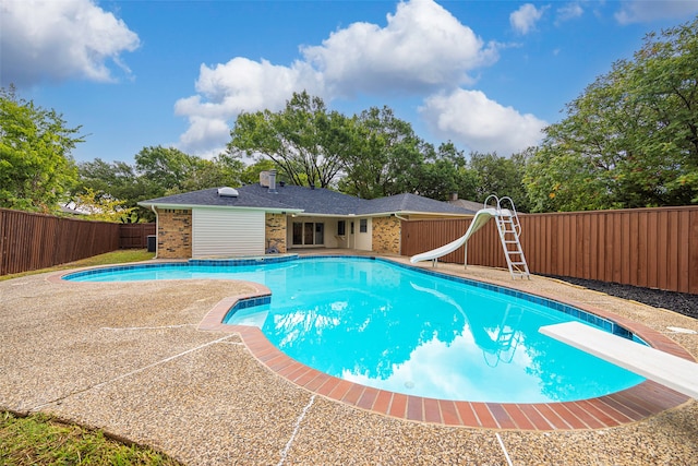 view of pool featuring a diving board and a water slide