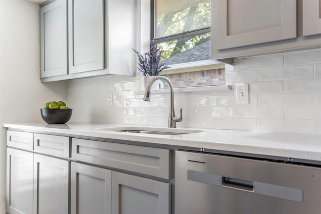 kitchen with sink, tasteful backsplash, light stone countertops, gray cabinets, and dishwasher