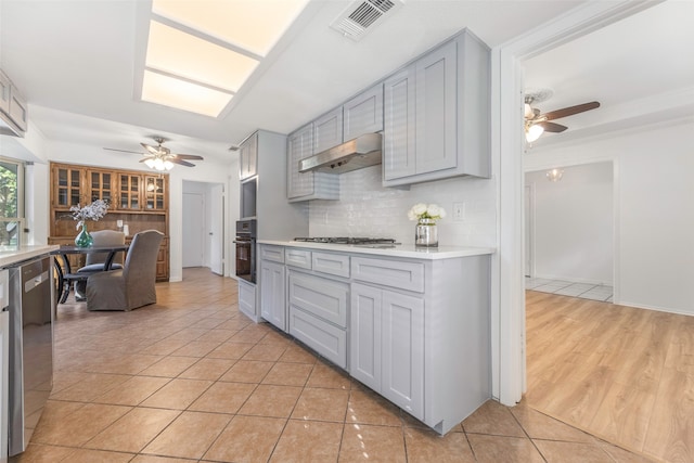 kitchen featuring gray cabinetry, backsplash, appliances with stainless steel finishes, light hardwood / wood-style floors, and ceiling fan