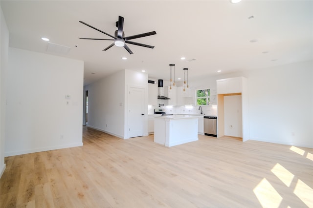 kitchen featuring white cabinetry, wall chimney range hood, a kitchen island, decorative light fixtures, and ceiling fan