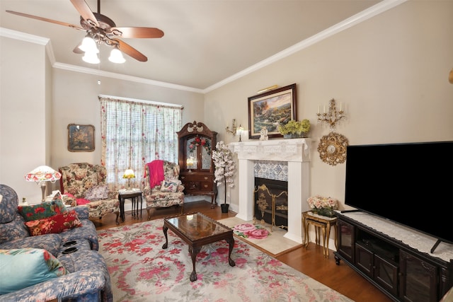 living room featuring ceiling fan, a fireplace, wood-type flooring, and ornamental molding