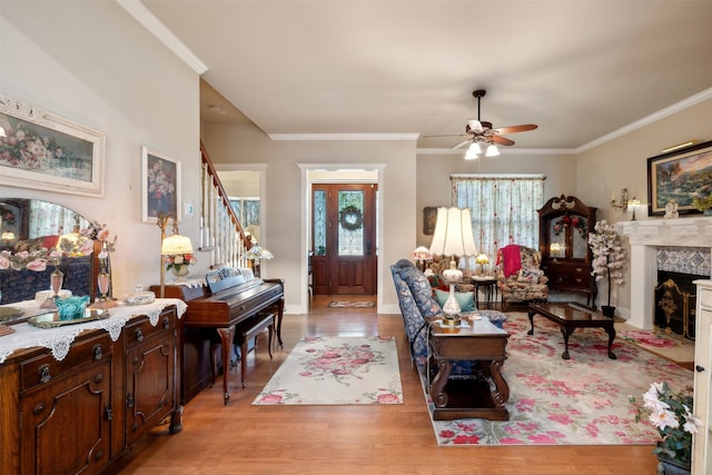 living room with light hardwood / wood-style flooring, ceiling fan, and ornamental molding