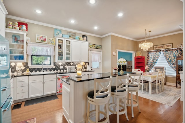 kitchen with pendant lighting, sink, stainless steel dishwasher, light wood-type flooring, and white cabinetry