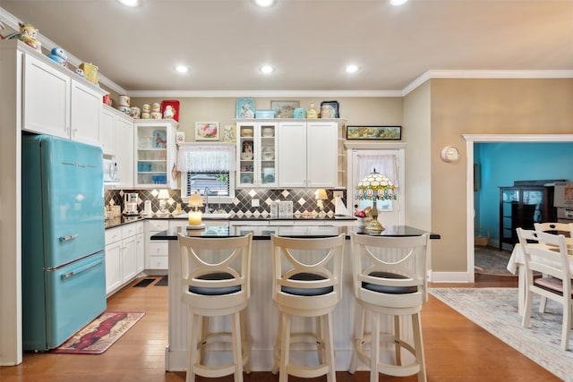 kitchen featuring tasteful backsplash, stainless steel fridge, light hardwood / wood-style floors, white cabinets, and ornamental molding