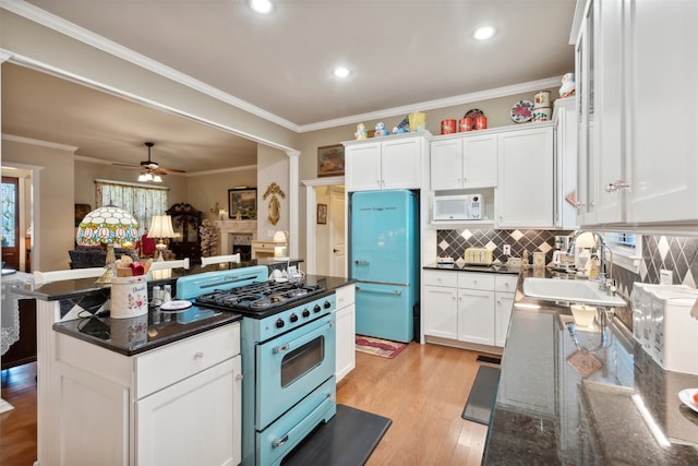 kitchen featuring white cabinets, light wood-type flooring, fridge, and gas range