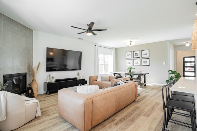 living room featuring a fireplace, a healthy amount of sunlight, light hardwood / wood-style flooring, and ceiling fan