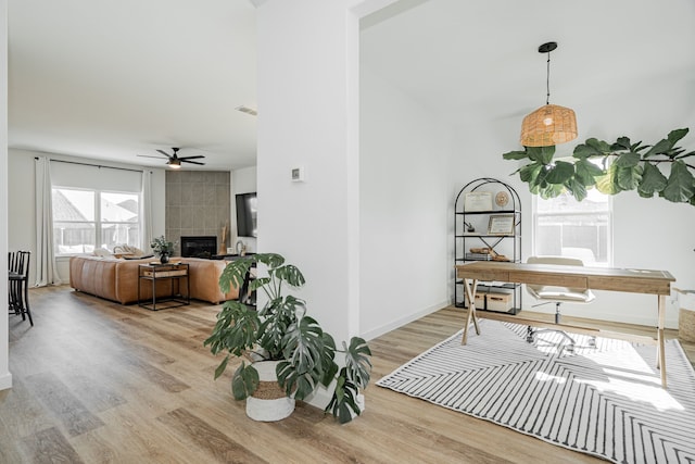 interior space featuring light hardwood / wood-style flooring, ceiling fan, and a tile fireplace