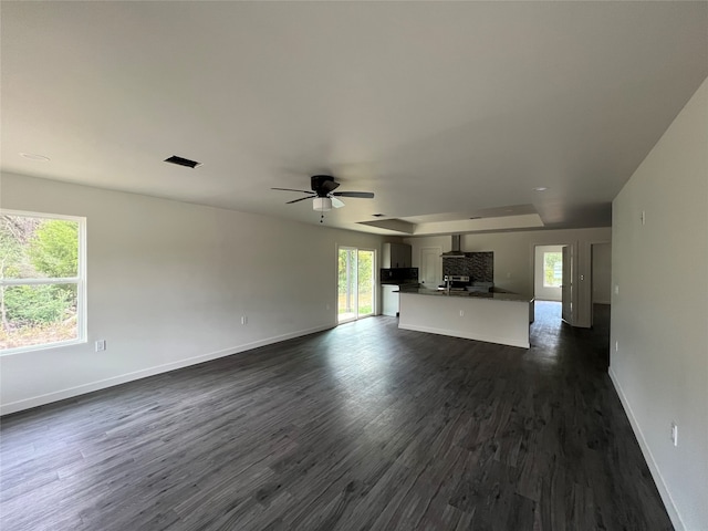 unfurnished living room featuring ceiling fan, dark hardwood / wood-style floors, and plenty of natural light