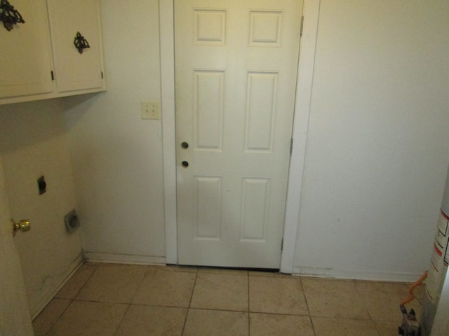 clothes washing area with light tile patterned flooring, cabinets, and hookup for an electric dryer