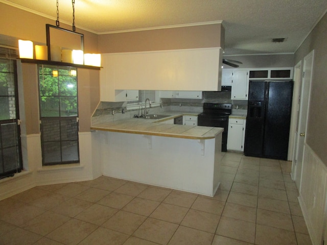 kitchen with white cabinets, sink, black appliances, kitchen peninsula, and a kitchen bar