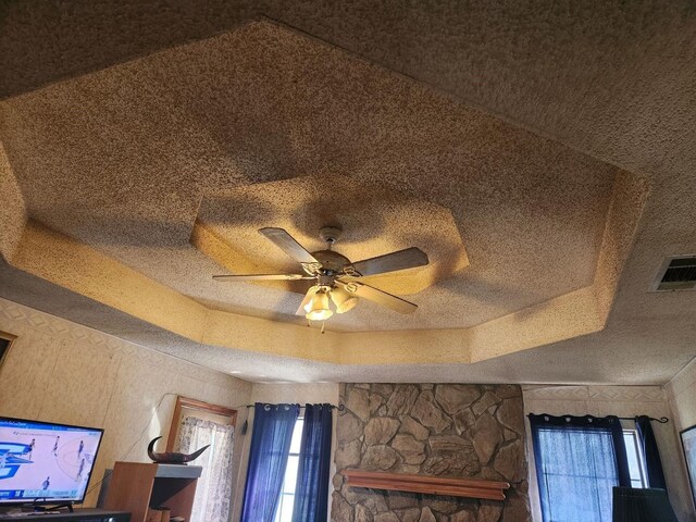 details featuring a textured ceiling, a raised ceiling, and ceiling fan