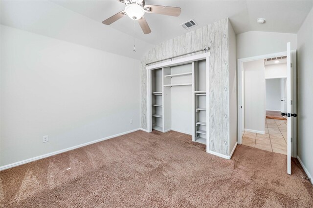 unfurnished bedroom featuring a closet, light colored carpet, vaulted ceiling, and ceiling fan