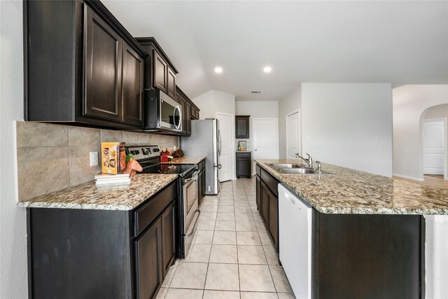 kitchen with sink, light tile patterned floors, light stone countertops, appliances with stainless steel finishes, and dark brown cabinets