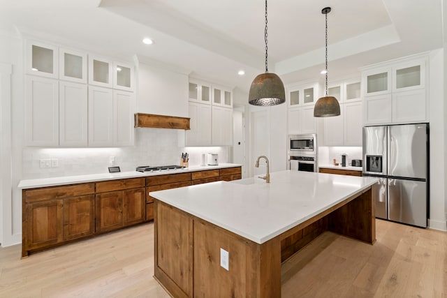 kitchen featuring white cabinetry, light hardwood / wood-style flooring, stainless steel appliances, sink, and a center island with sink