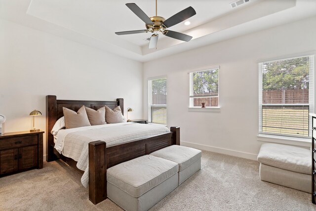 carpeted bedroom with ceiling fan and a raised ceiling