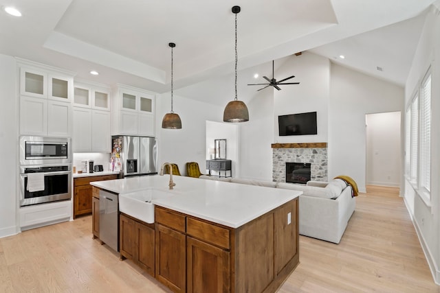 kitchen featuring a fireplace, appliances with stainless steel finishes, a center island, sink, and white cabinetry