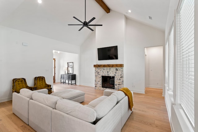 living room with plenty of natural light, light hardwood / wood-style flooring, ceiling fan, and a stone fireplace