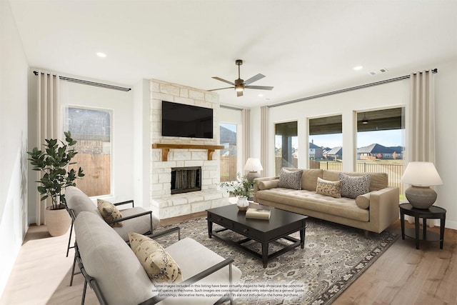 living room with ceiling fan, light hardwood / wood-style floors, and a fireplace