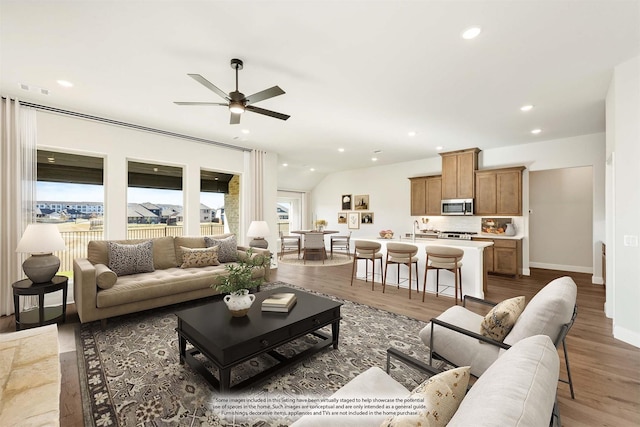 living room featuring ceiling fan, lofted ceiling, sink, and hardwood / wood-style floors