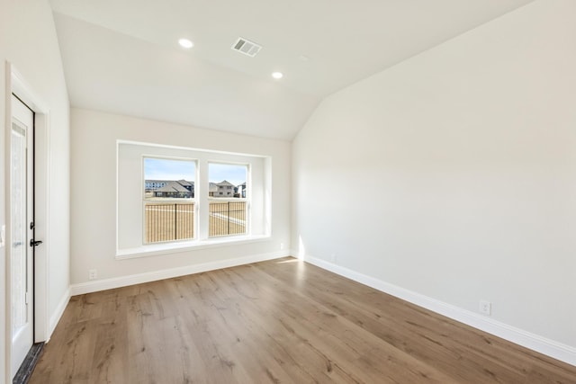 spare room featuring light hardwood / wood-style floors and vaulted ceiling