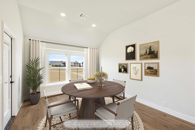 dining area featuring hardwood / wood-style flooring and vaulted ceiling