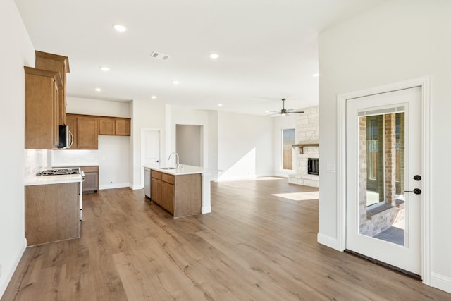 kitchen with sink, light hardwood / wood-style flooring, ceiling fan, an island with sink, and stainless steel appliances