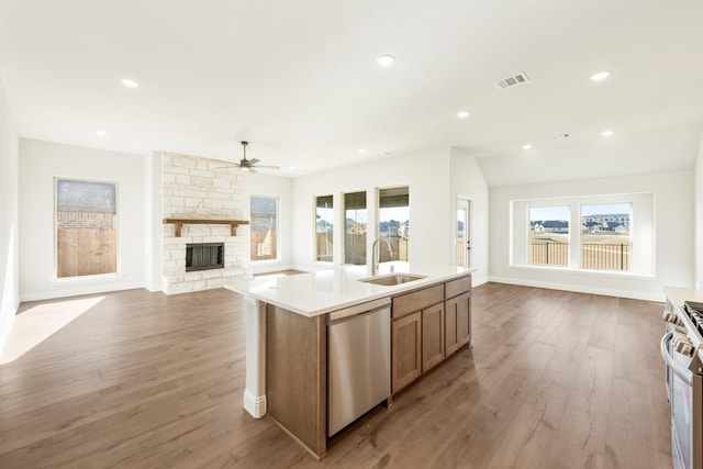 kitchen with sink, an island with sink, stainless steel appliances, and light wood-type flooring