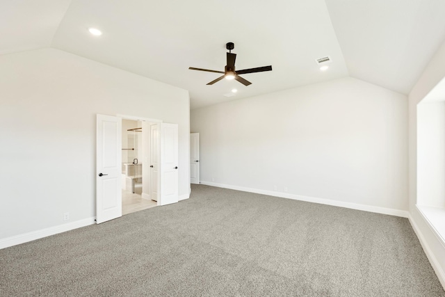 unfurnished bedroom featuring ceiling fan, ensuite bathroom, light colored carpet, and lofted ceiling