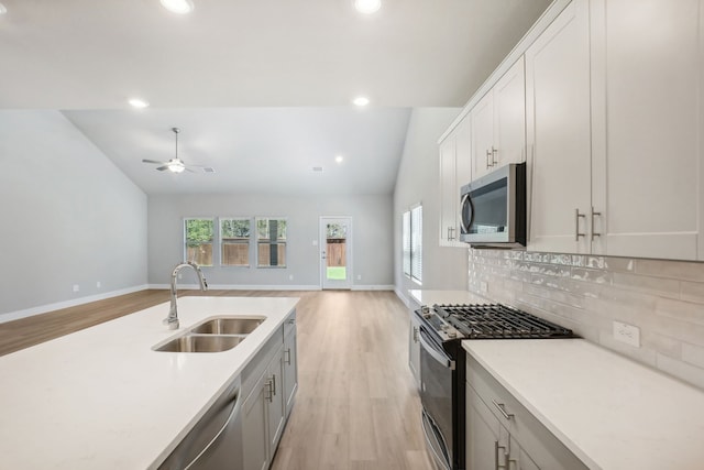 kitchen featuring decorative backsplash, light hardwood / wood-style flooring, sink, lofted ceiling, and appliances with stainless steel finishes